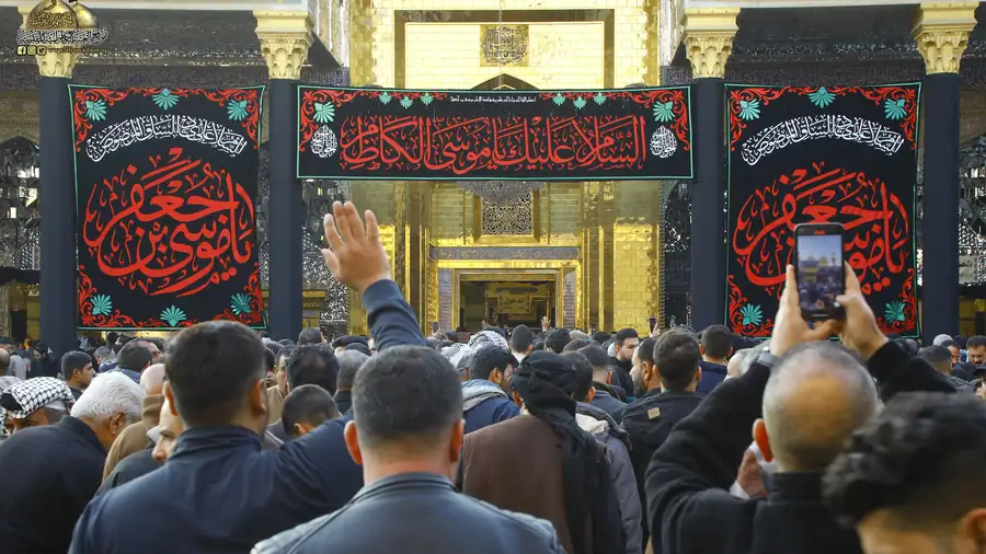 زائر يصوّر بهاتفه أمام باب الحرم الكاظمي